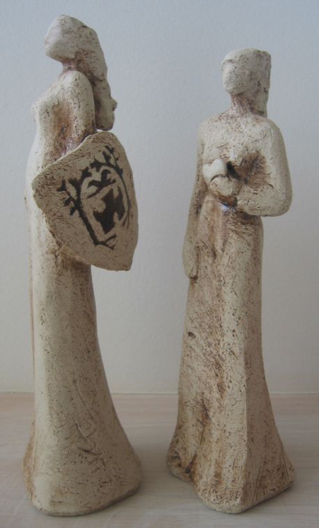 Statuetterne er udført af Keramiker Lene Kersting, Jels. Statuette "kvinde med hjerte i hånden" symboliserer næstekærlighed. Statuette "kvinde med skjold og byvåben", symboliserer byens stolthed.